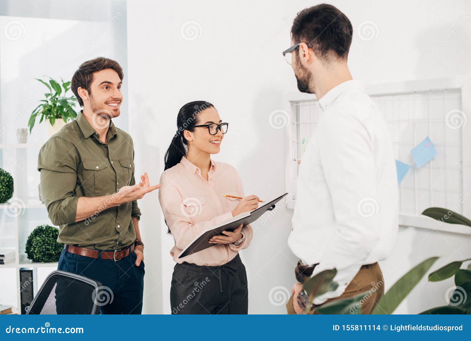 Happy Office Managers Standing in Front of Board with Post it Notes and