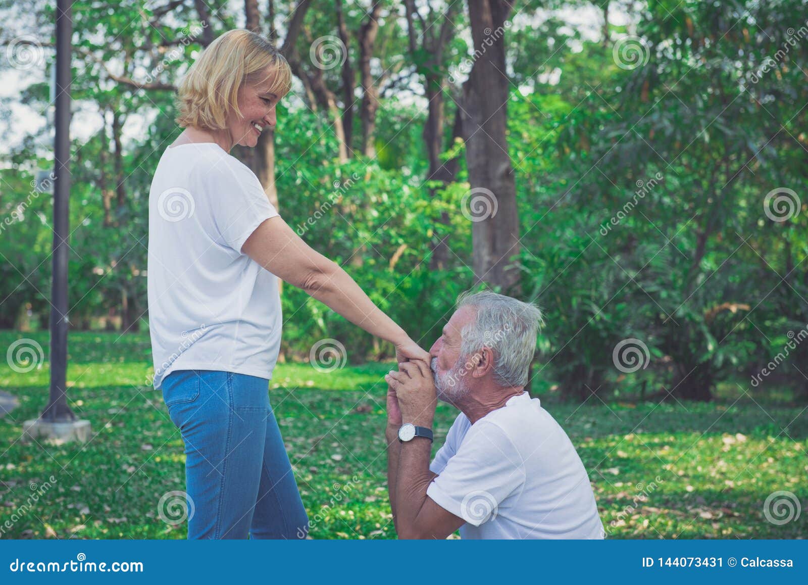 happy old man kiss his wife hand at the park
