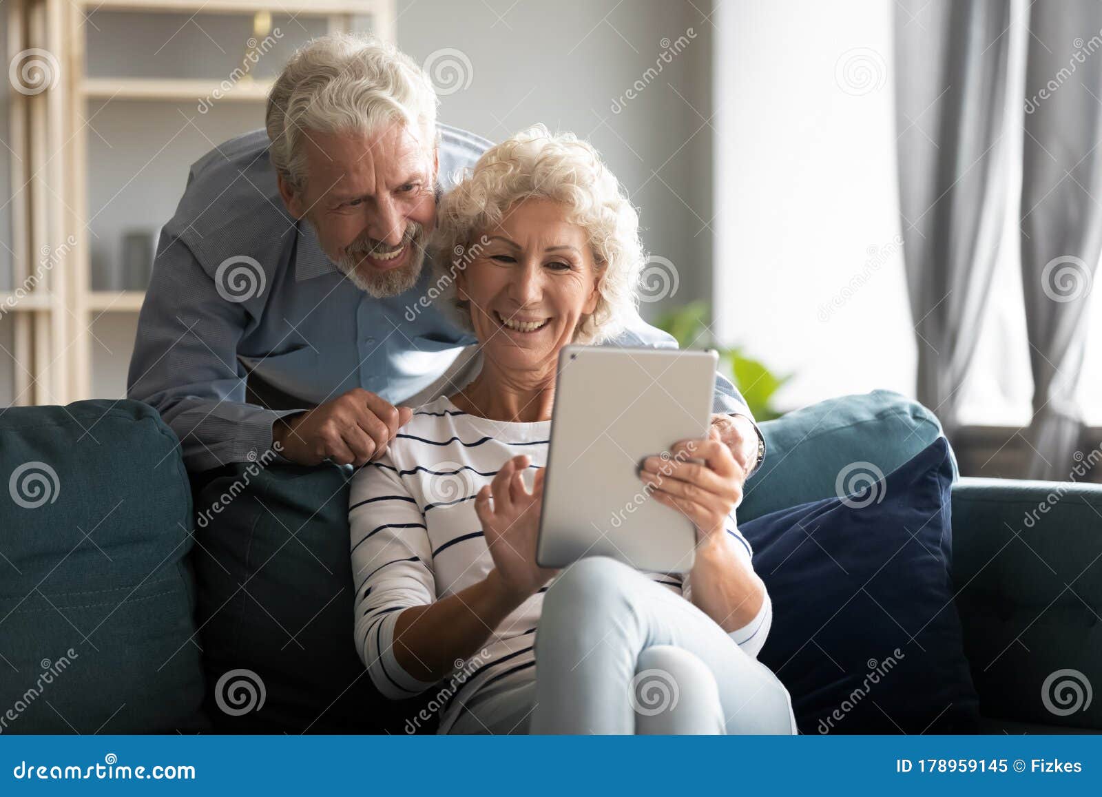 happy older couple using computer tablet together at home