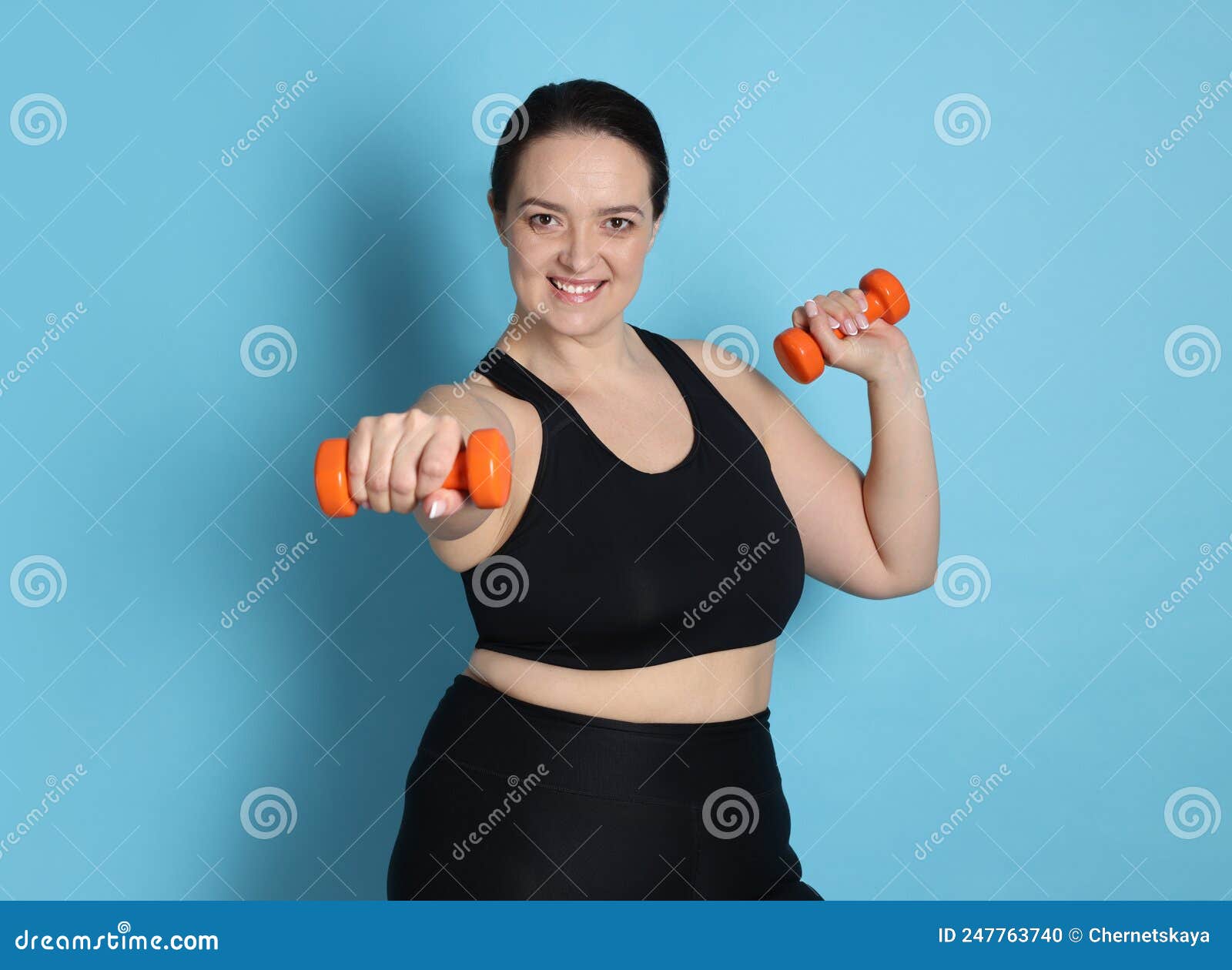 Happy Overweight Woman Doing Exercise with Dumbbells on Light Blue ...