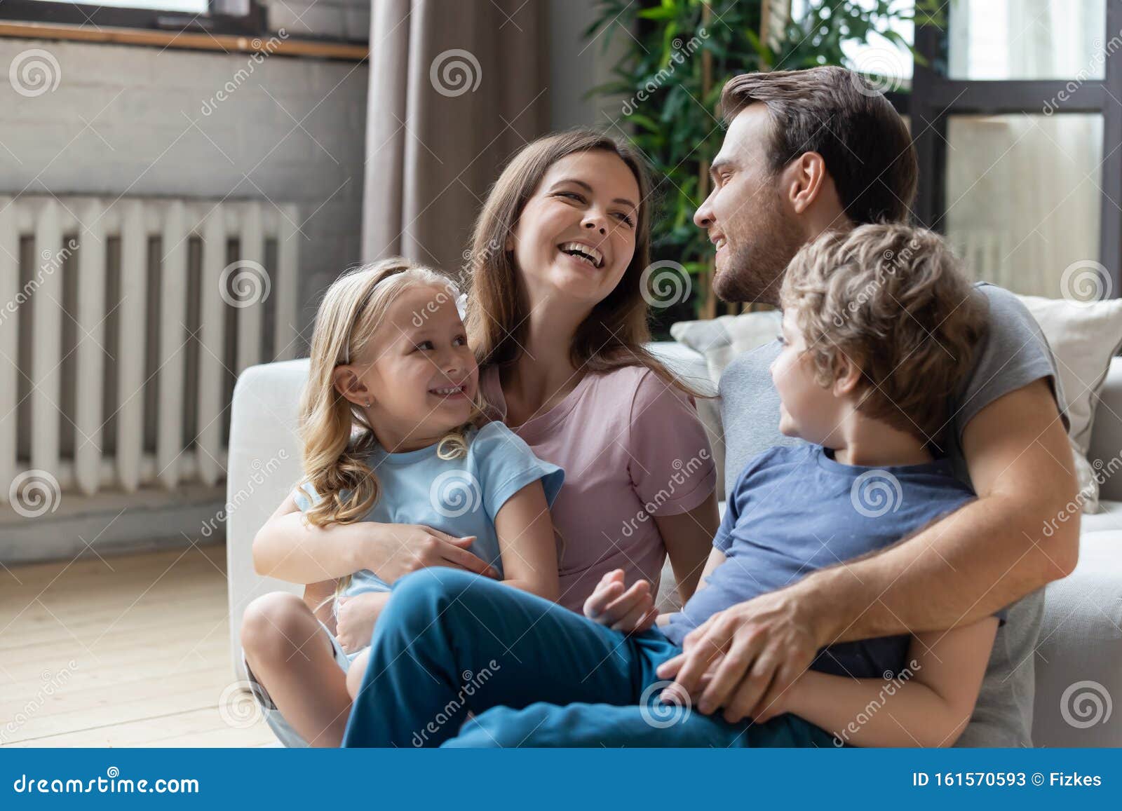 Happy Parents With Little Son And Daughter Sitting On Floor Stock Image