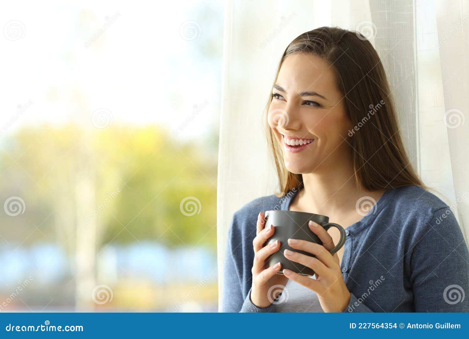 happy pensive woman looks at side beside a window