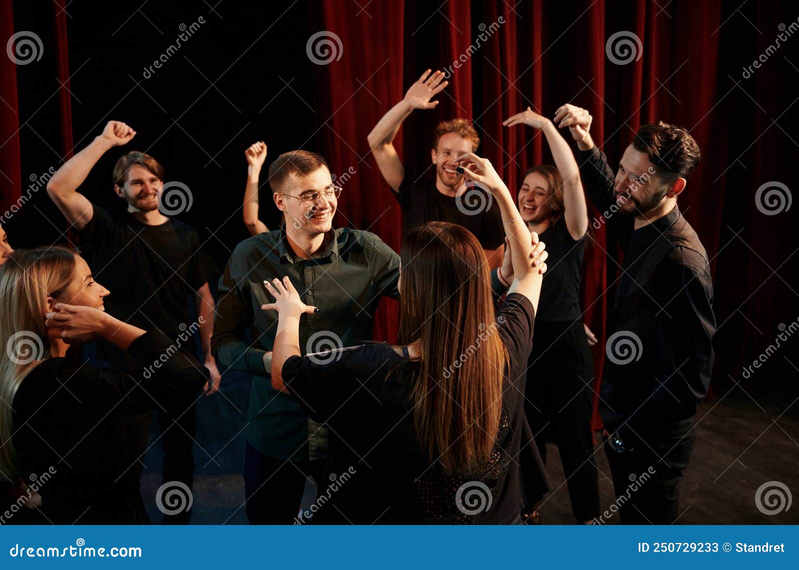 happy people celebrating success. group of actors in dark colored clothes on rehearsal in the theater