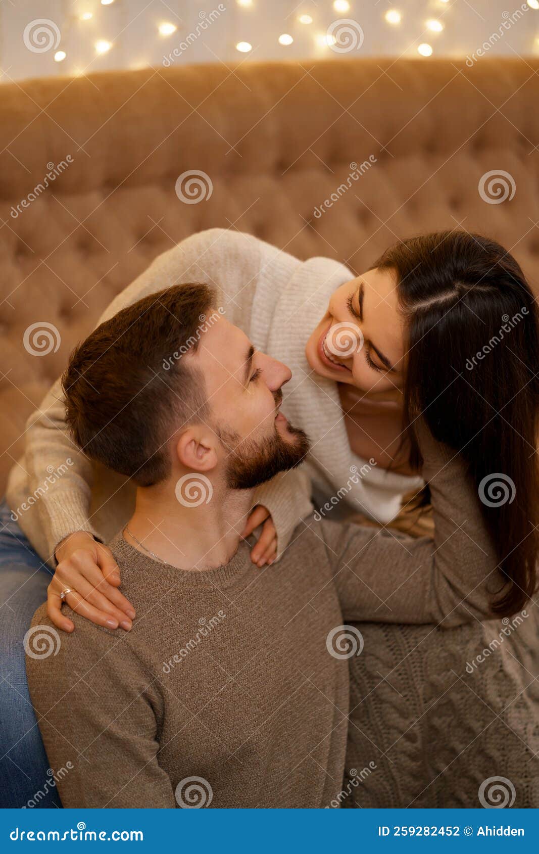 Happy Positive Young Couple Embracing Relaxing Sit on Sofa Stock Photo