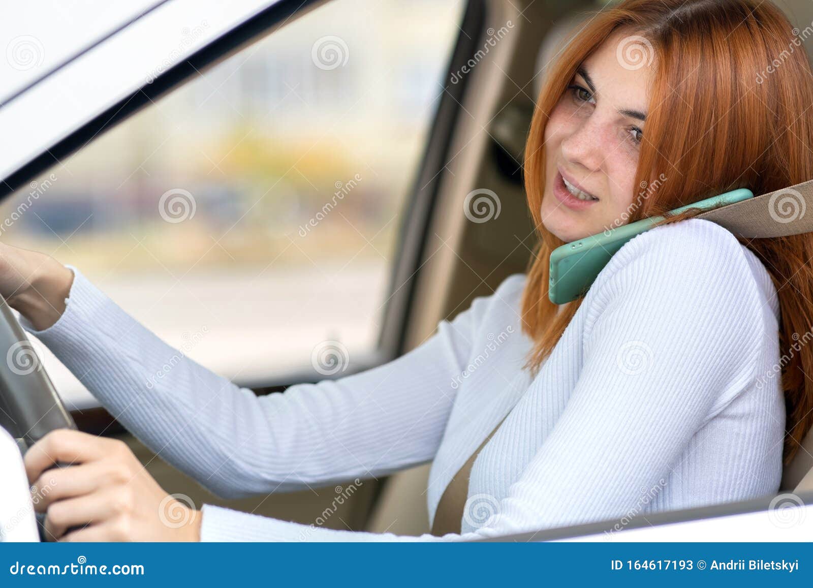 Happy Redhead Girl Talking on Her Mobile Phone Behind the Wheel Driving  