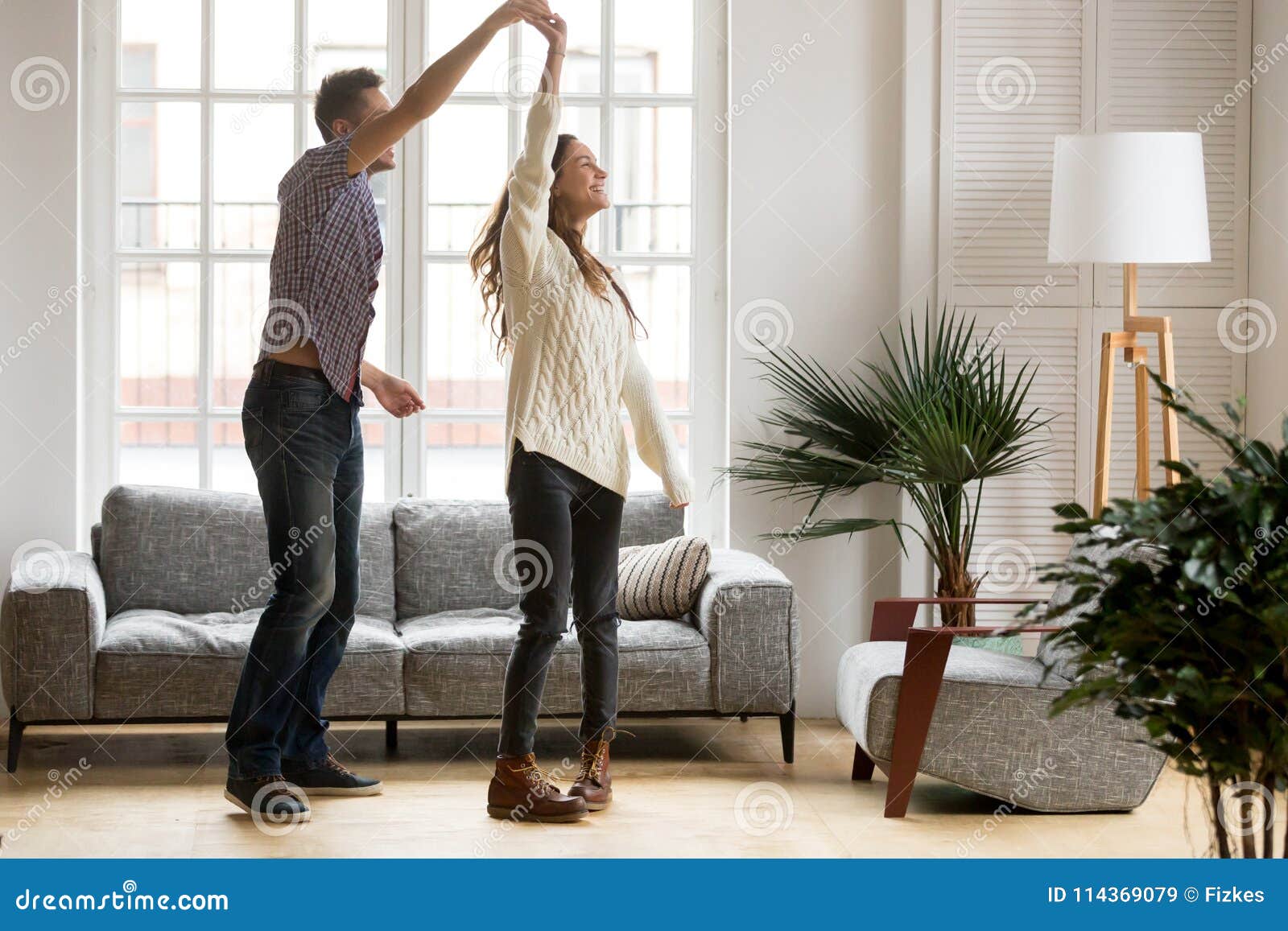 Happy Romantic Couple Dancing in Living Room at Home Together Stock