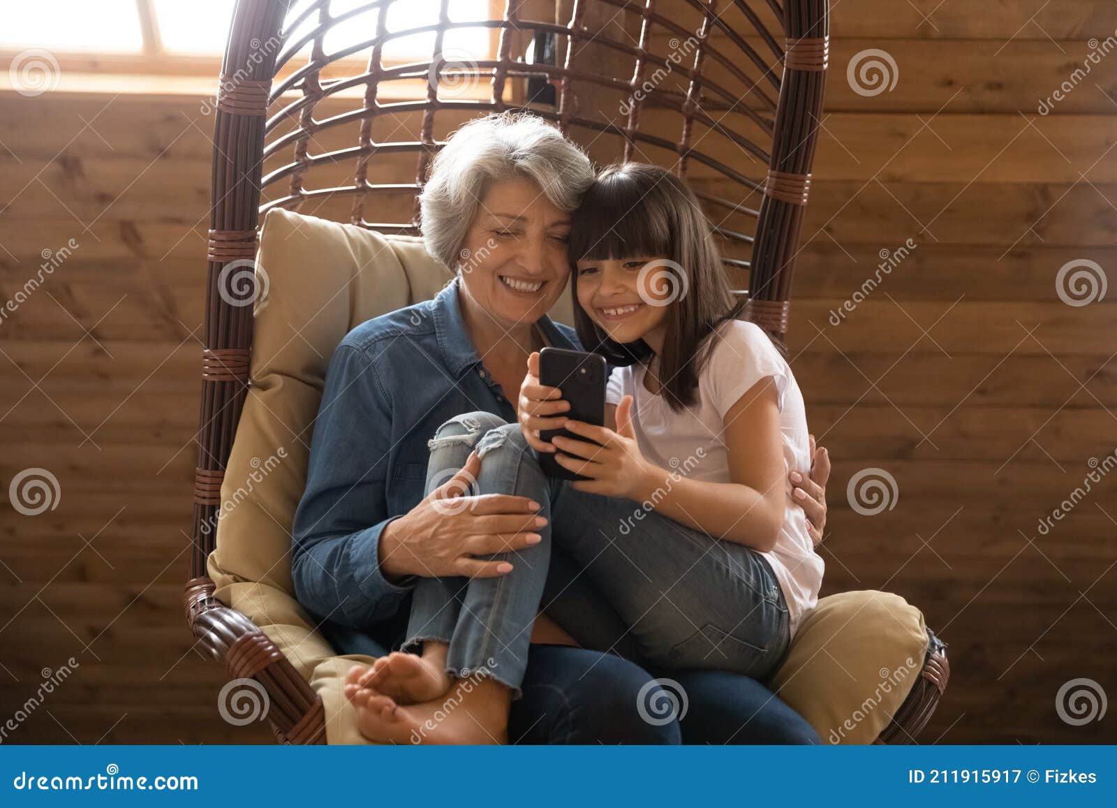 happy senior grandmother and granddaughter use smartphone laughing