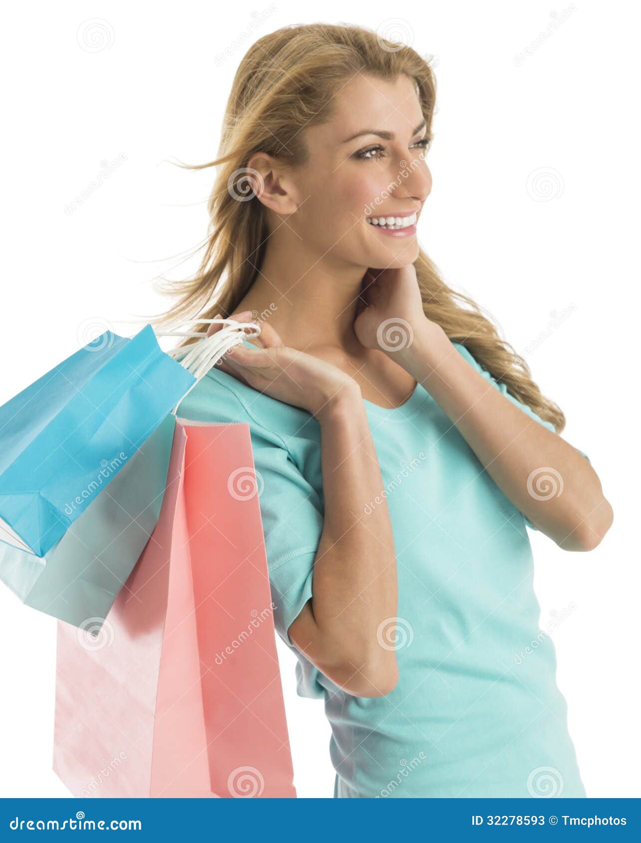 happy shopaholic woman looking away while carrying shopping bags