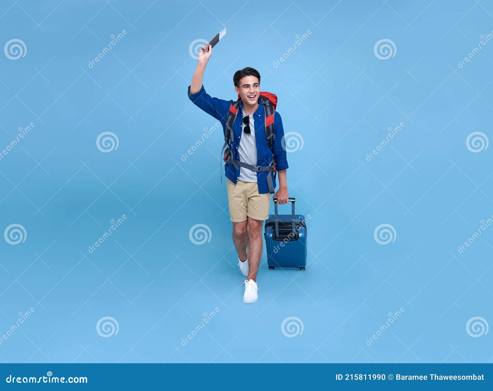 happy smiling asian bag packer man with passport and luggage enjoying their summer vacation getaway in blue background