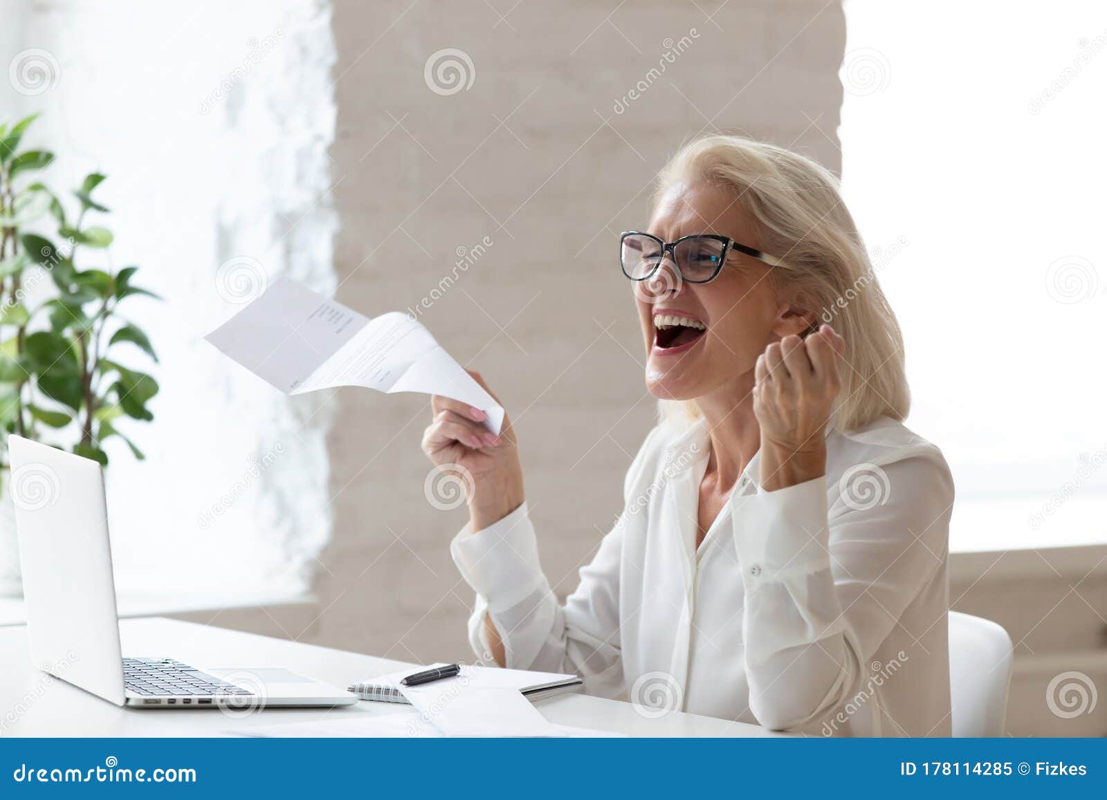 happy smiling 60 years old businesswoman using laptop.