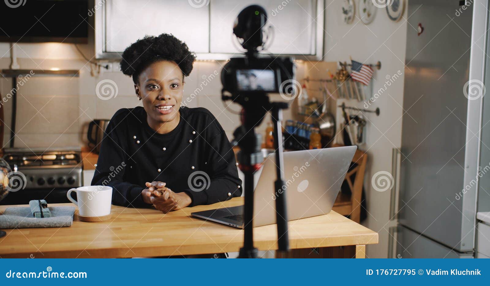 happy smiling young beautiful black vlogger woman filming new video using professional camera at home table slow motion.