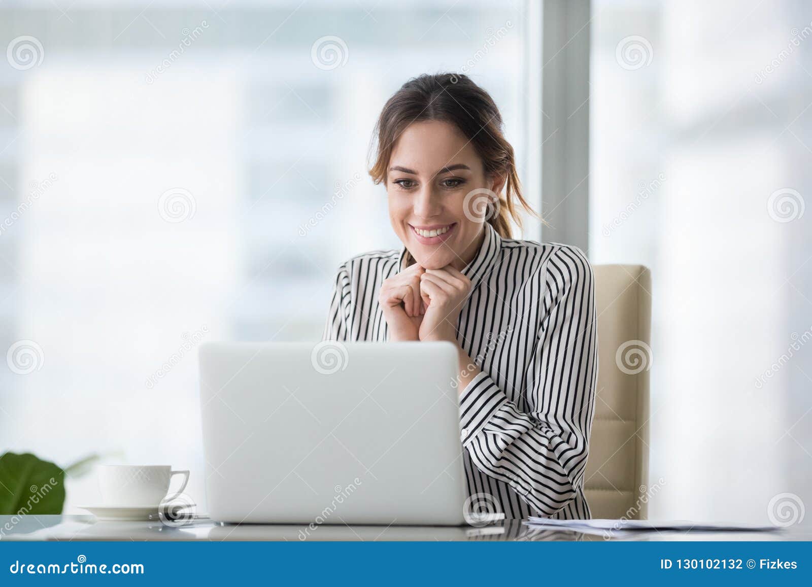 happy smiling young woman looking at laptop screen.