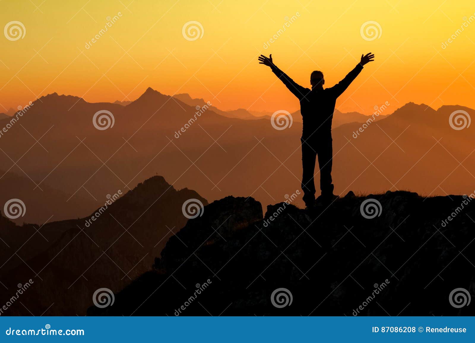 happy success winning man on summit arms up at sunset