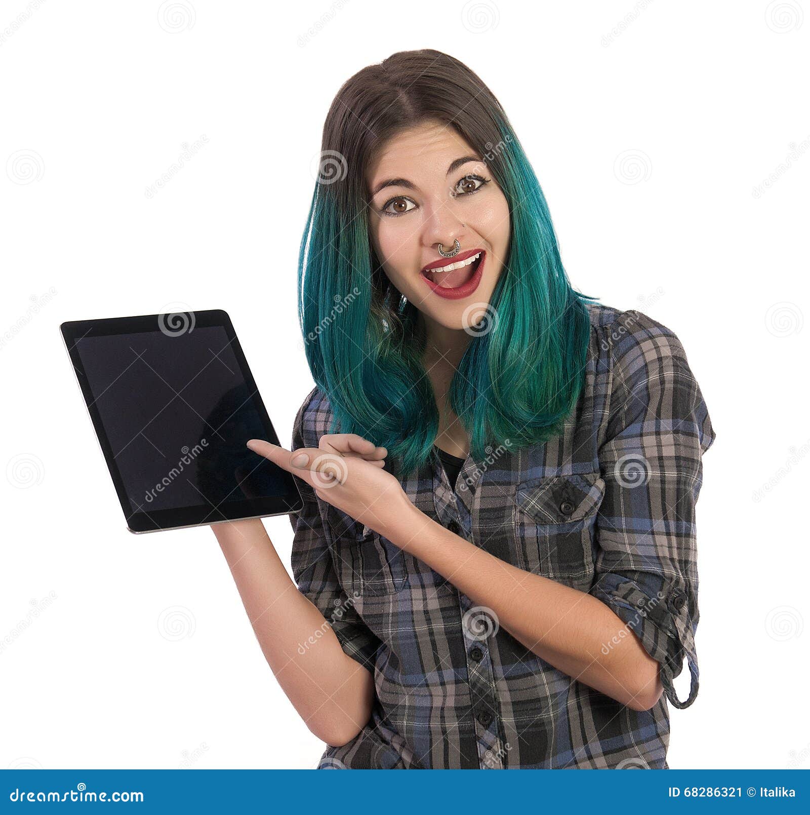 Happy and surprised girl showing you something on a digital tablet on white background. Pierced, turquoise haired and dressing up a plaid shirt.