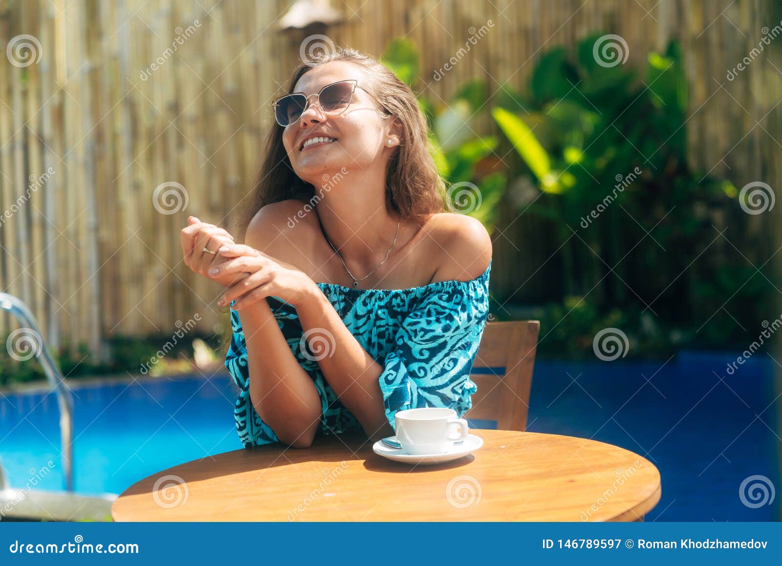 Happy Tanned Girl in Sunglasses Sits Outdoors at Table with Cups of ...