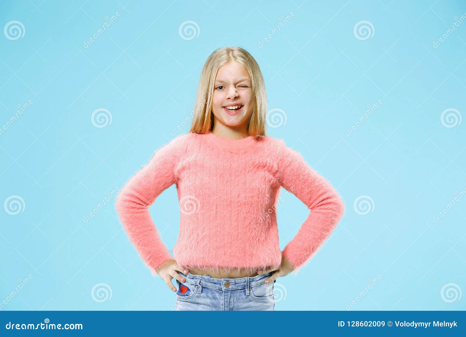 The Happy Teen Girl Standing And Smiling Against Orange 