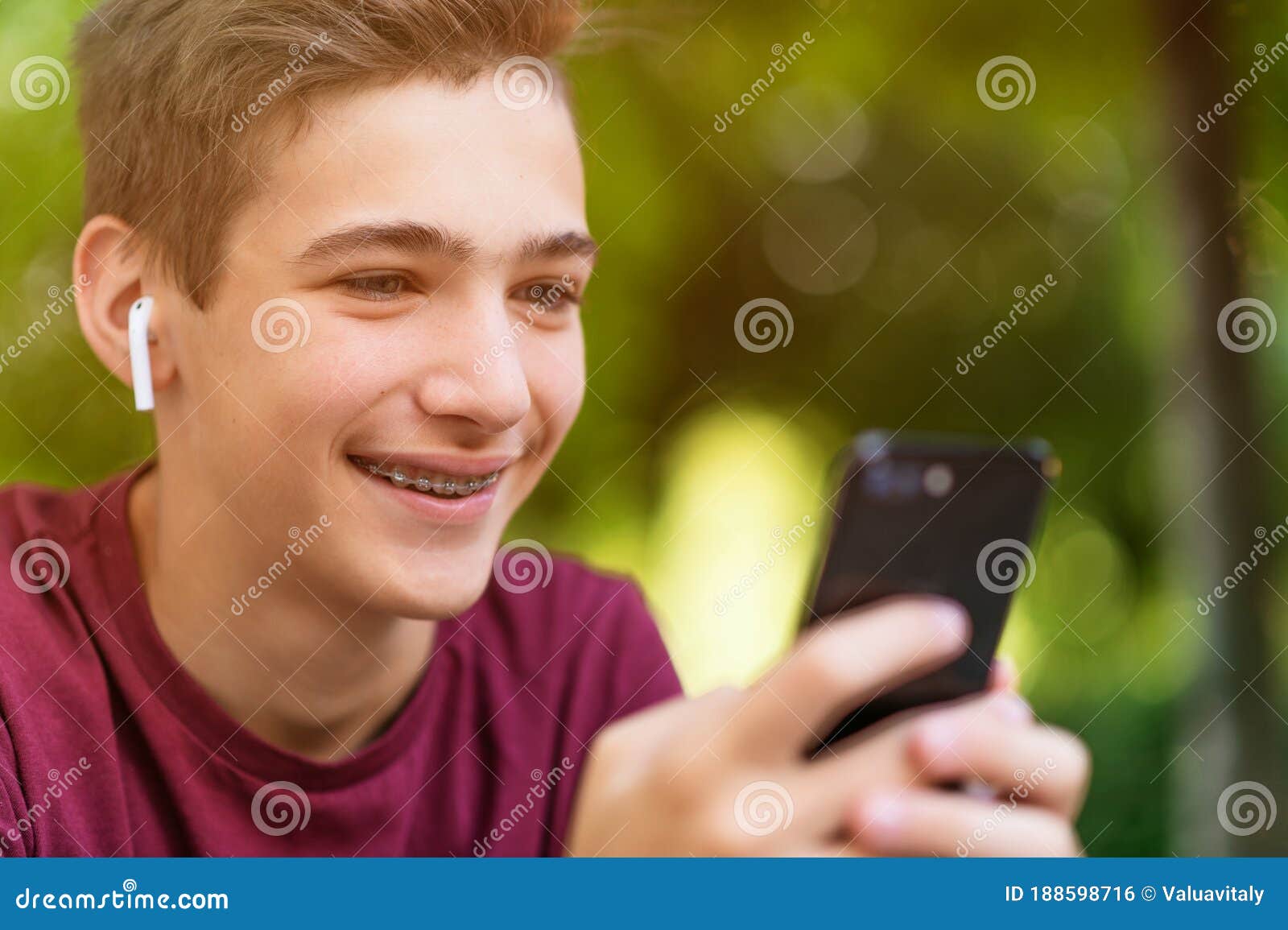 Happy Teenage Boy is Using Mobile Phone, Outdoors. Close-up Portrait of ...