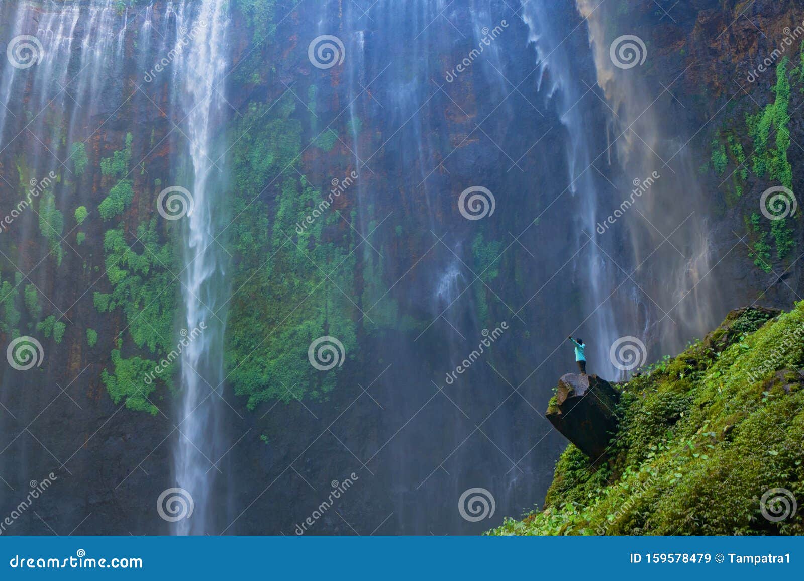 a happy tourist man watching sewu waterfall. the biggest waterfall in java island. nature landscape background of travel trip and