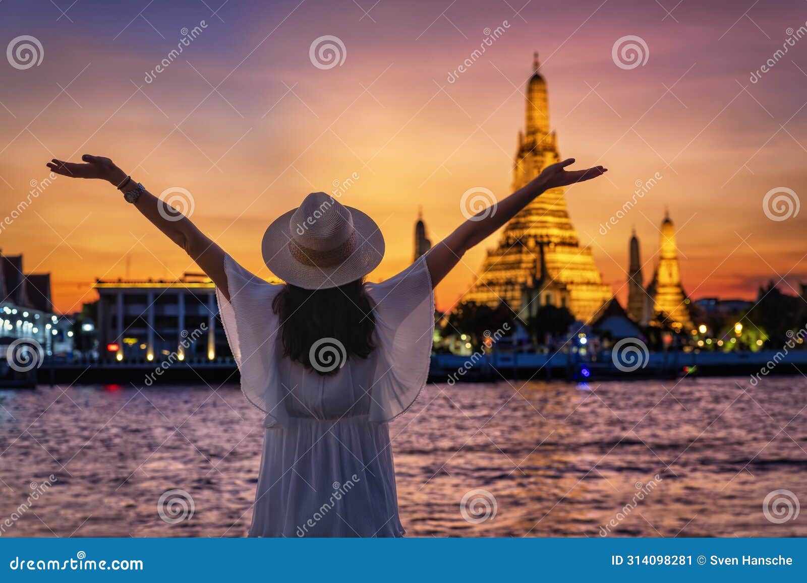a happy tourist woman enjoys the view of the illuminated wat arun temple in bangkok