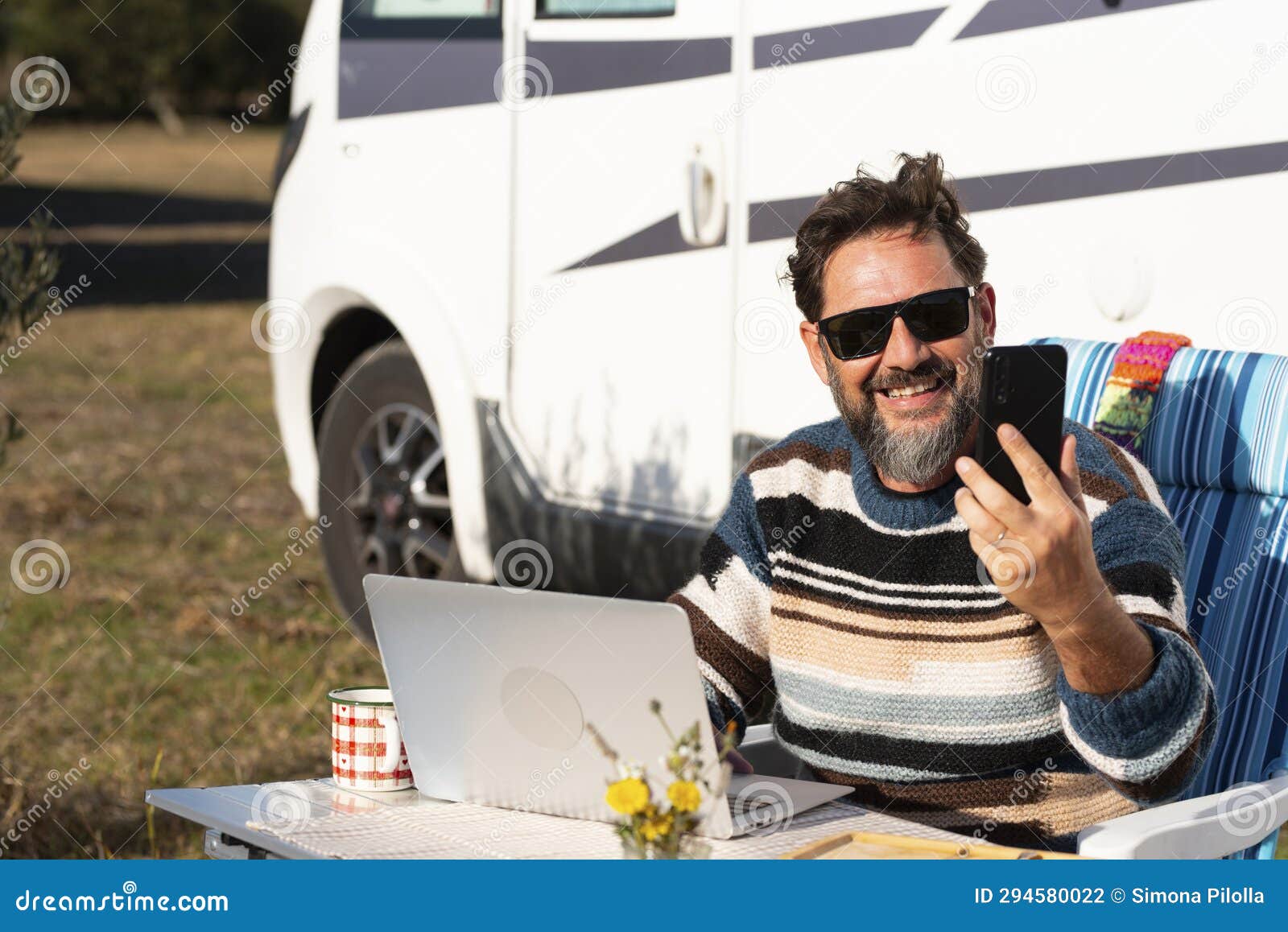 happy traveler work on laptop computer outside a camper van and use phone call to connect and call. one man smile and enjoy