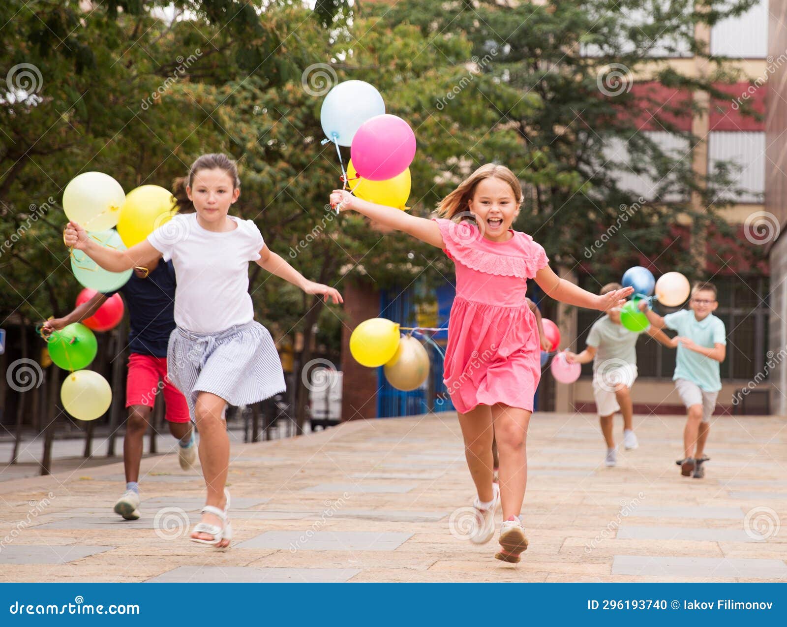 Happy Tweens Wth Colorful Balloons Chasing Each Other On City Street