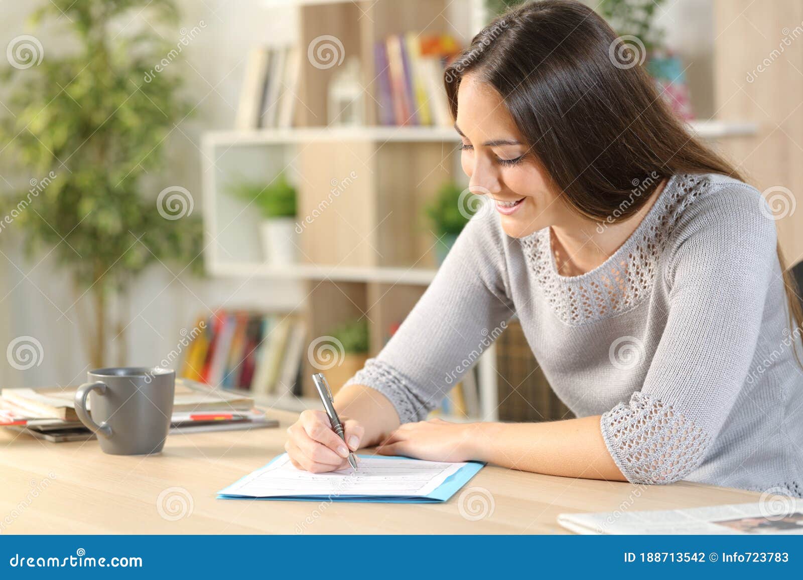 happy woman filling out form on a desk at home
