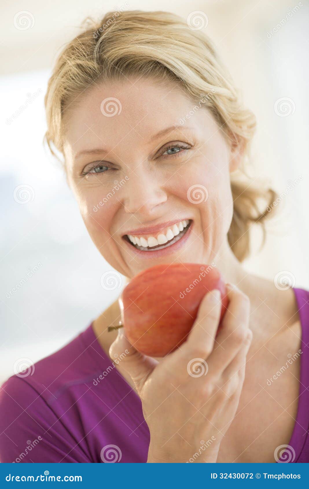 Happy Woman Holding Fresh Apple In Gym. Portrait of happy mature woman holding fresh apple in gym