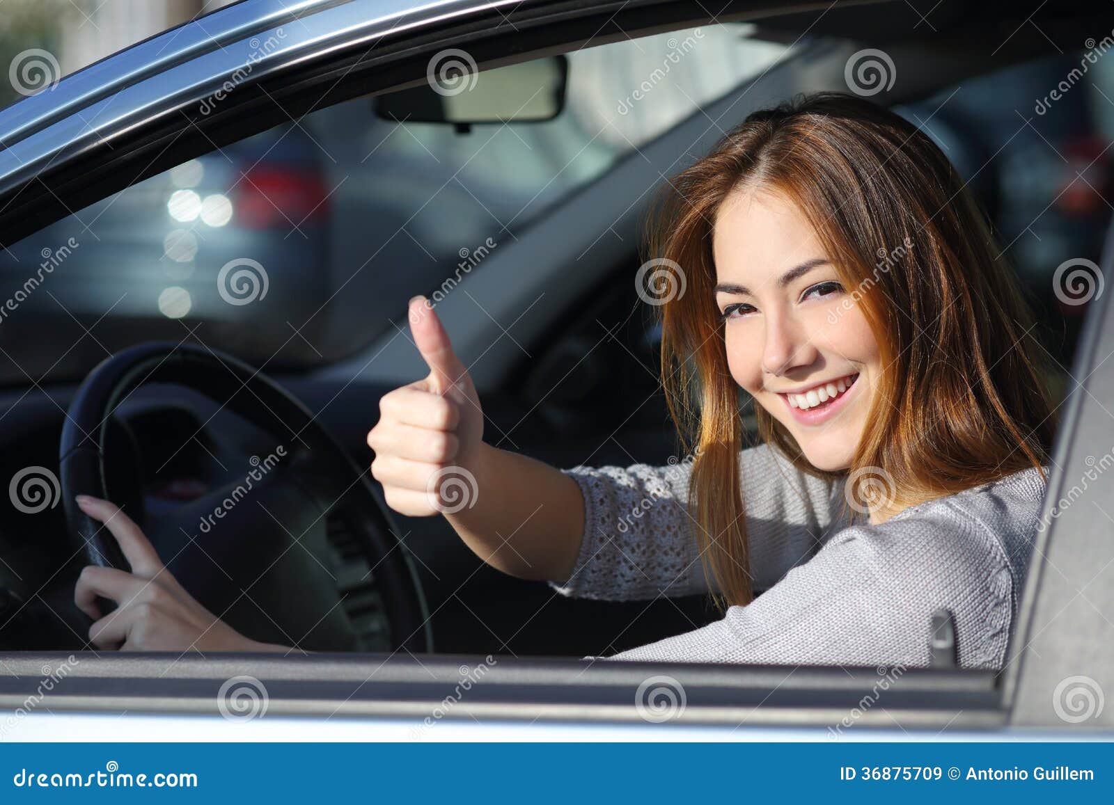 happy woman inside a car gesturing thumb up