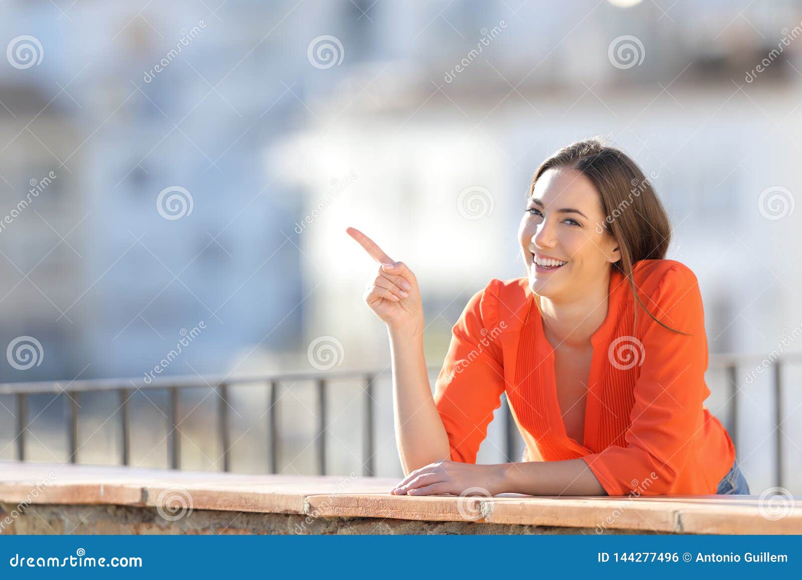 happy woman pointing at side in a town outskirts