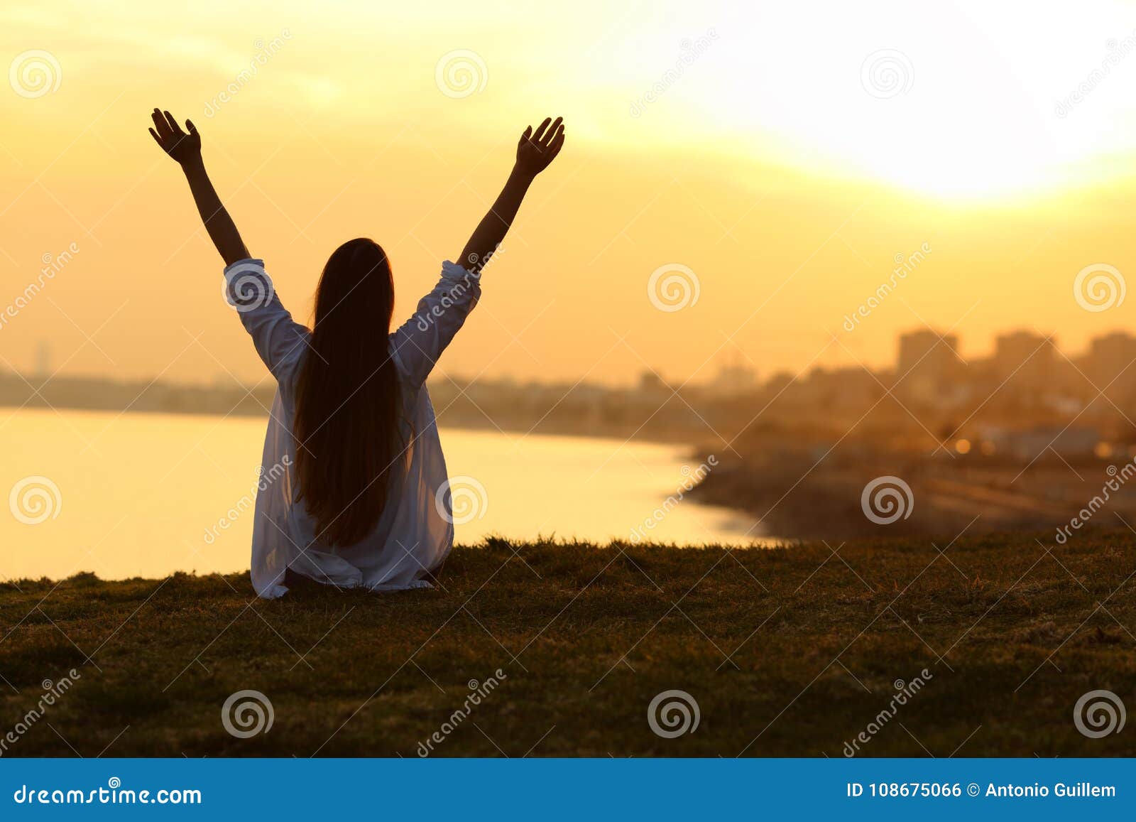 happy woman seeing city at sunset and raising arms