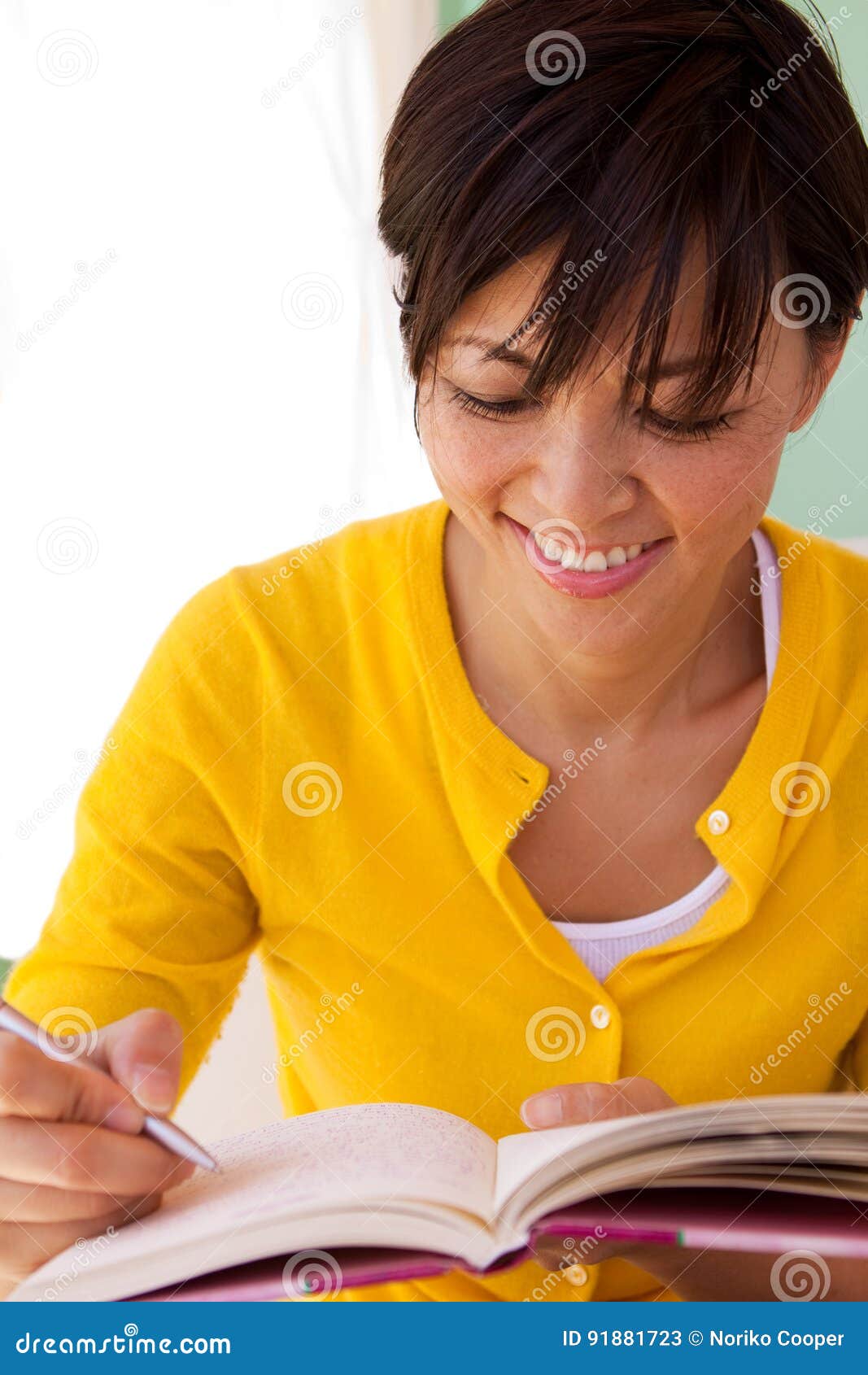 happy woman sitting inside writing in a journal.