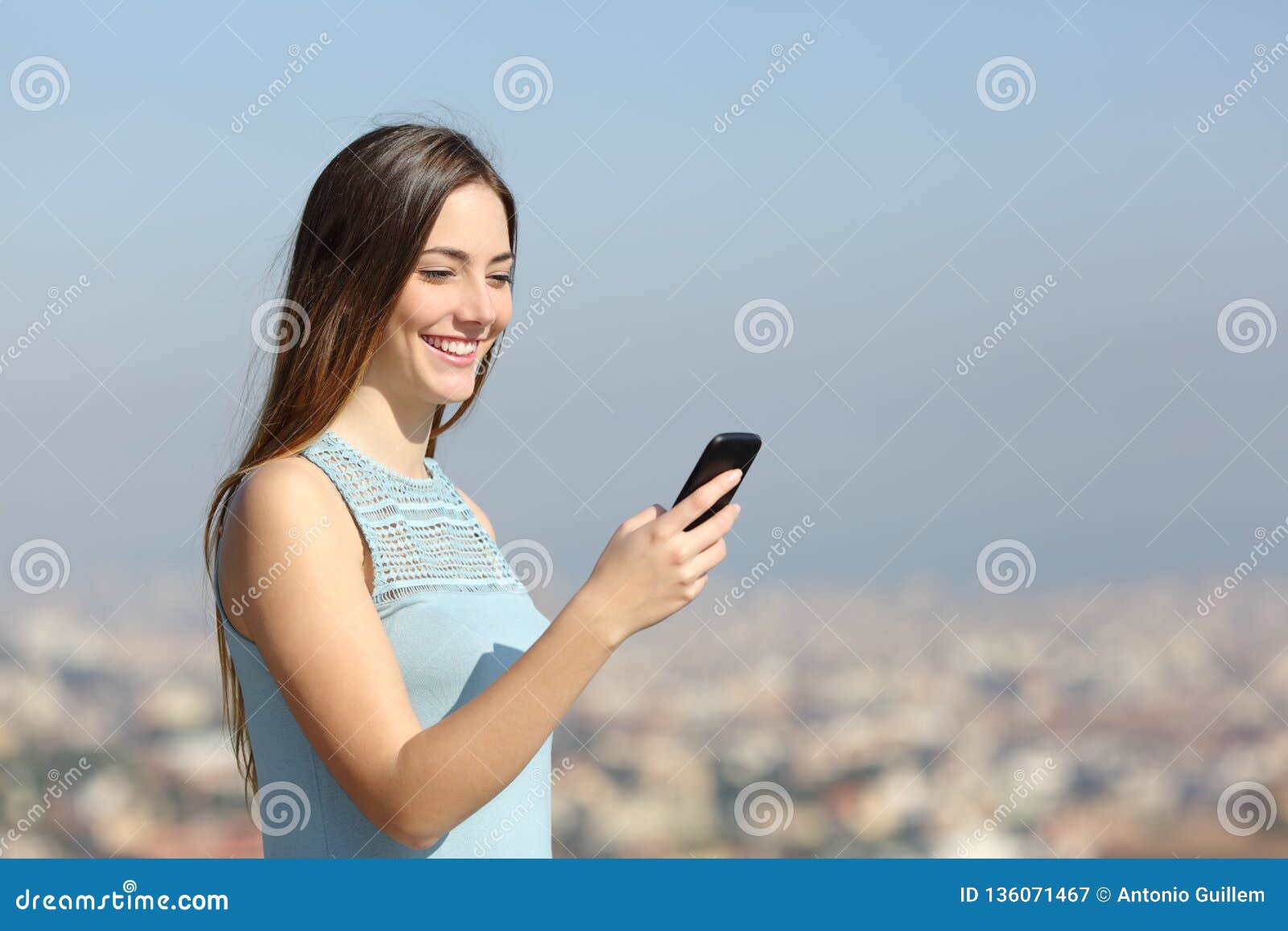 happy woman using a smart phone in a city outskirts