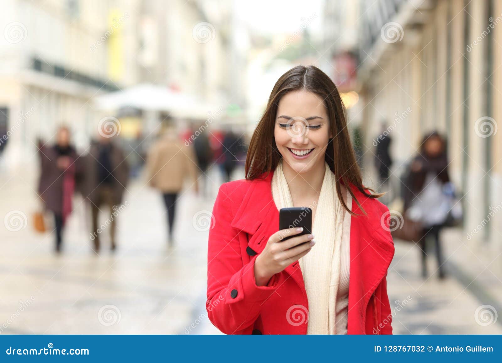 happy woman walking using a cellphone in the street