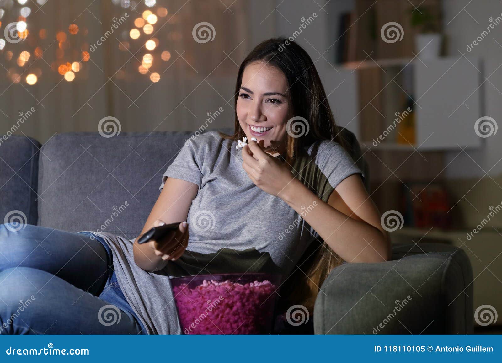 happy woman watching tv in the night at home
