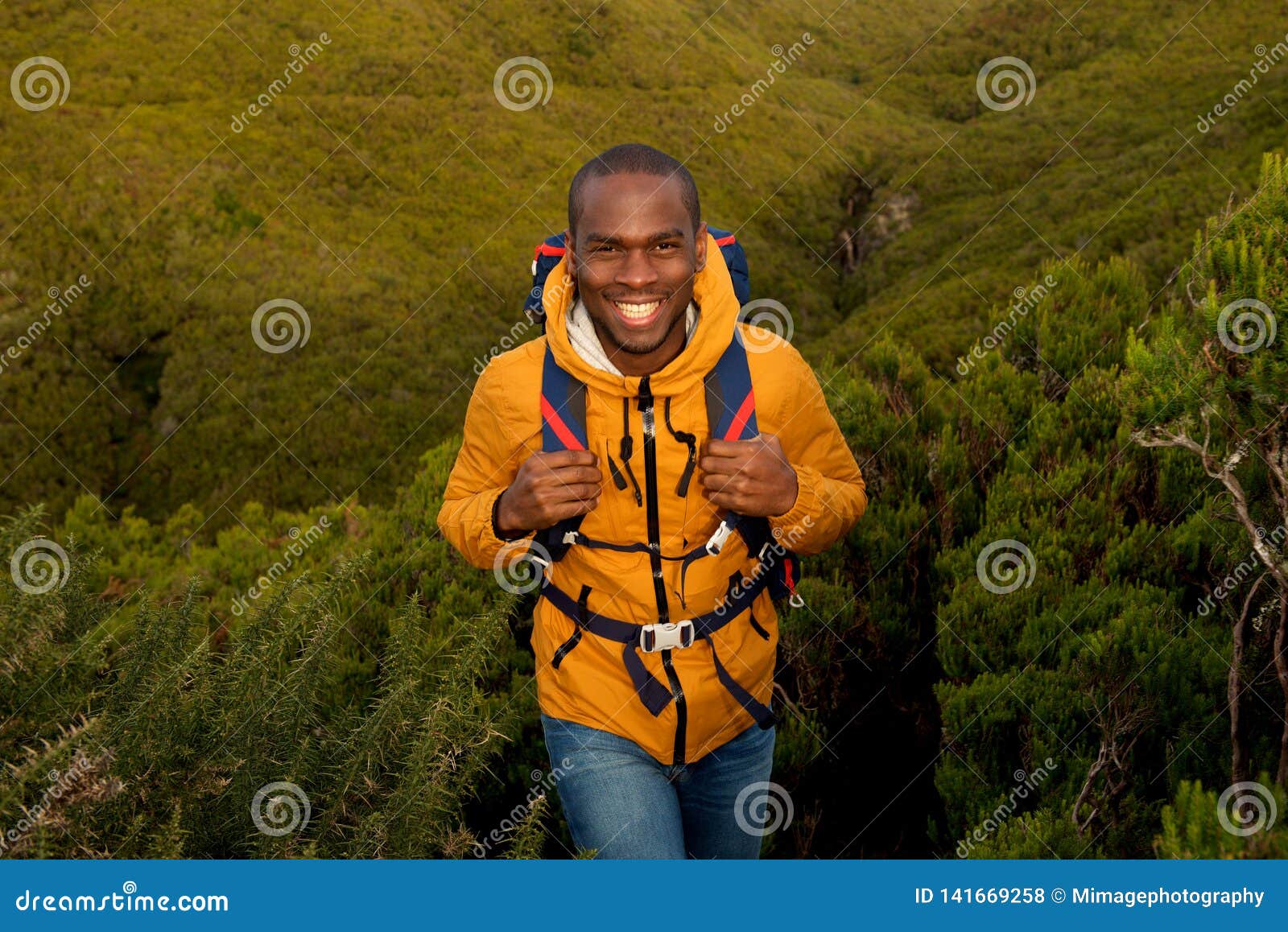 happy young black man hiking in nature with backpack