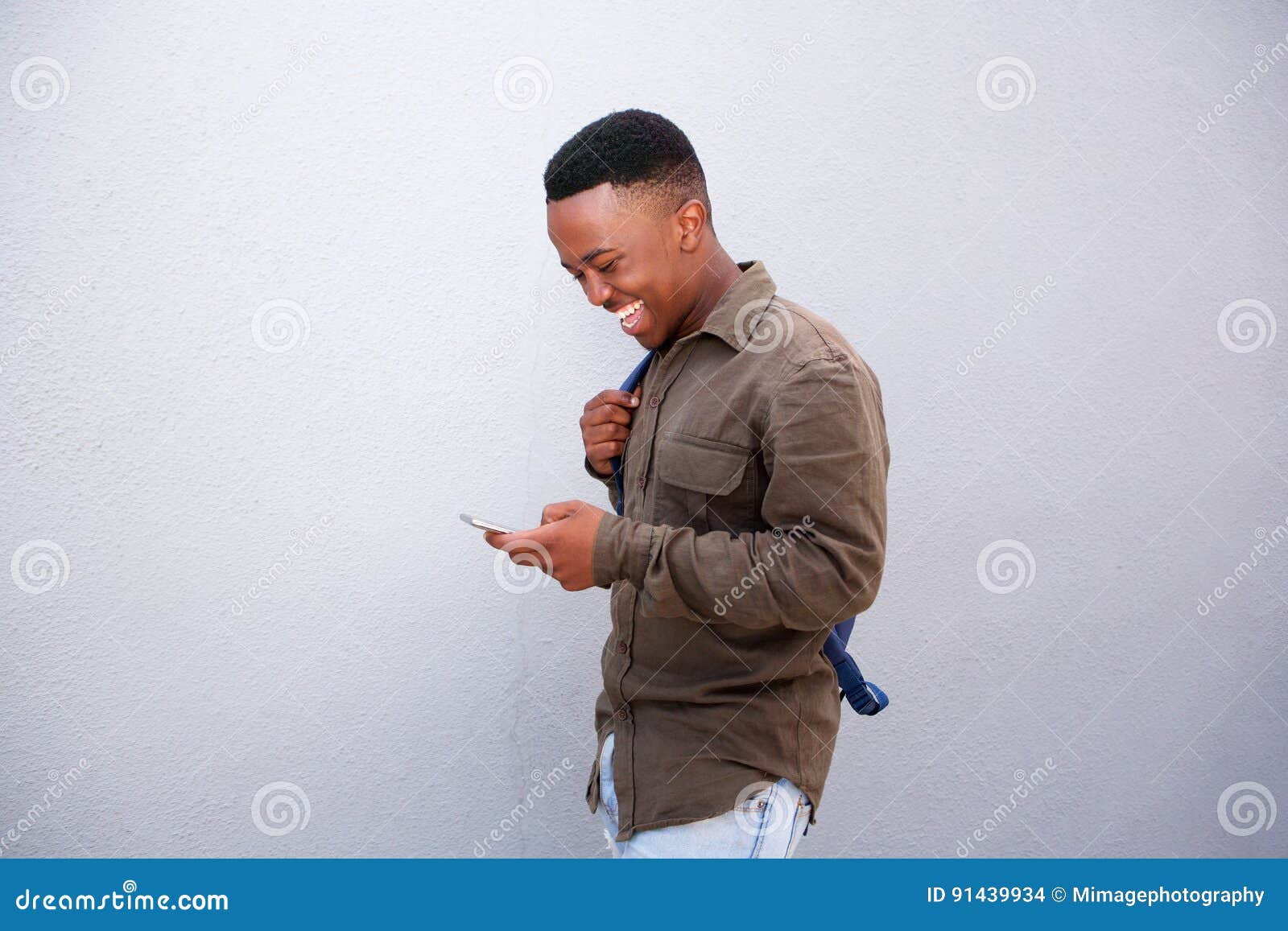 happy young black man looking at cellphone