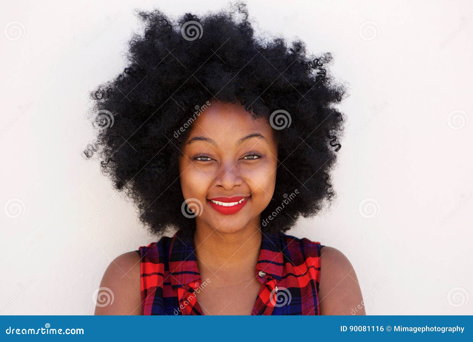 happy young black woman with afro hairstyle by white wall