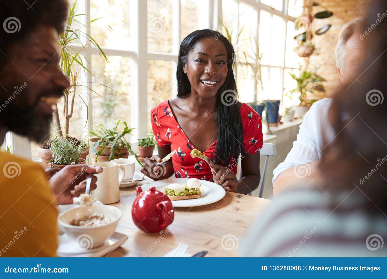 happy young black woman eating brunch with friends at a cafe