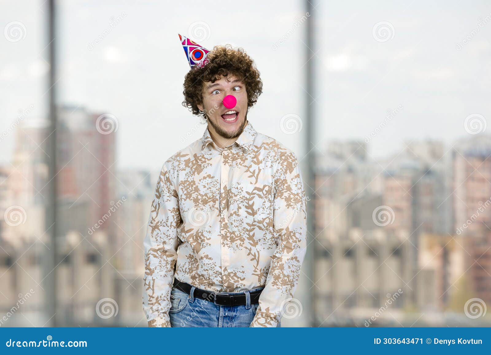 happy young caucasian guy with clown nose fooling around making funny faces.
