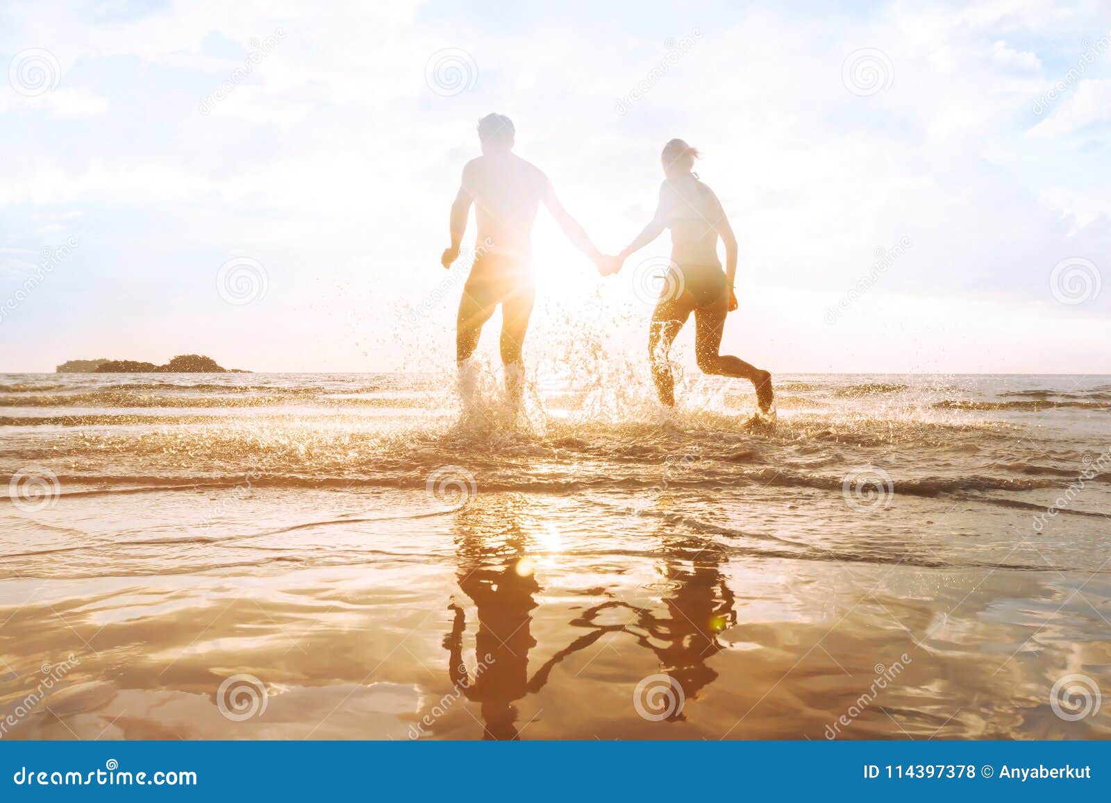 happy young couple having fun on the beach at sunset, water splash
