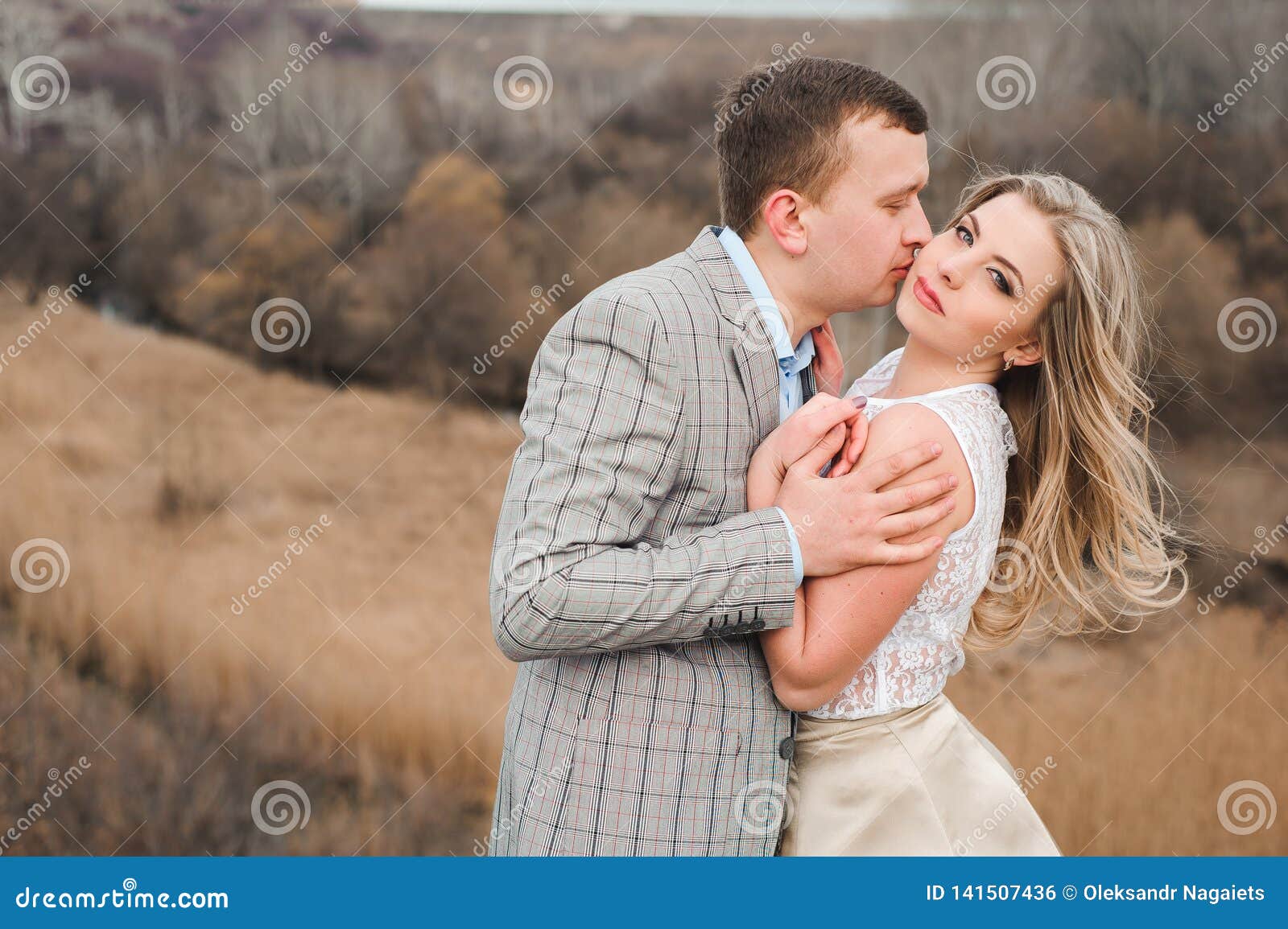 Photo of Hugging Couple Standing In Front of Bare Trees 