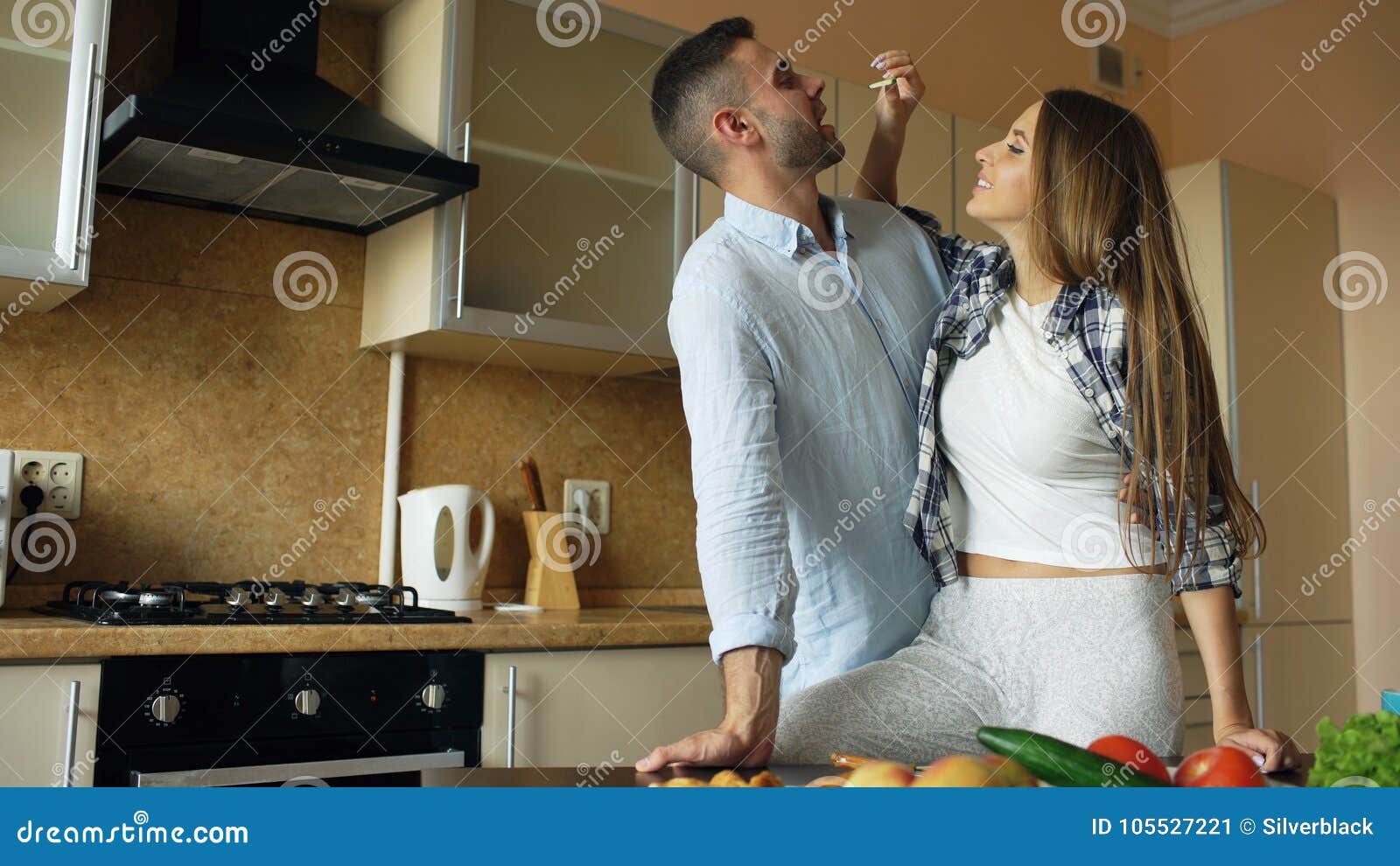 Happy Young Couple In The Kitchen Attractive Woman Feeding Her