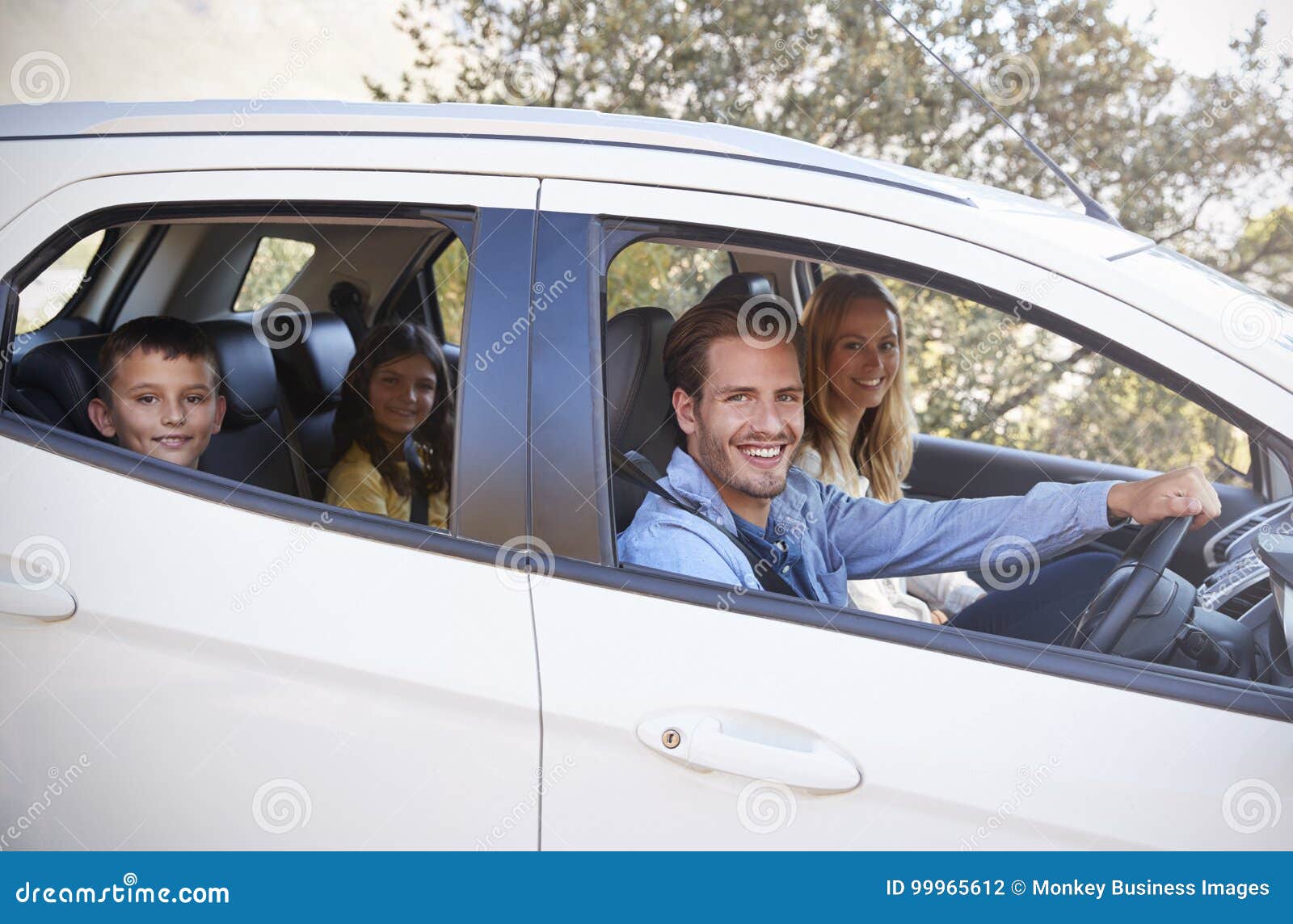 happy young family driving in their car looking to camera