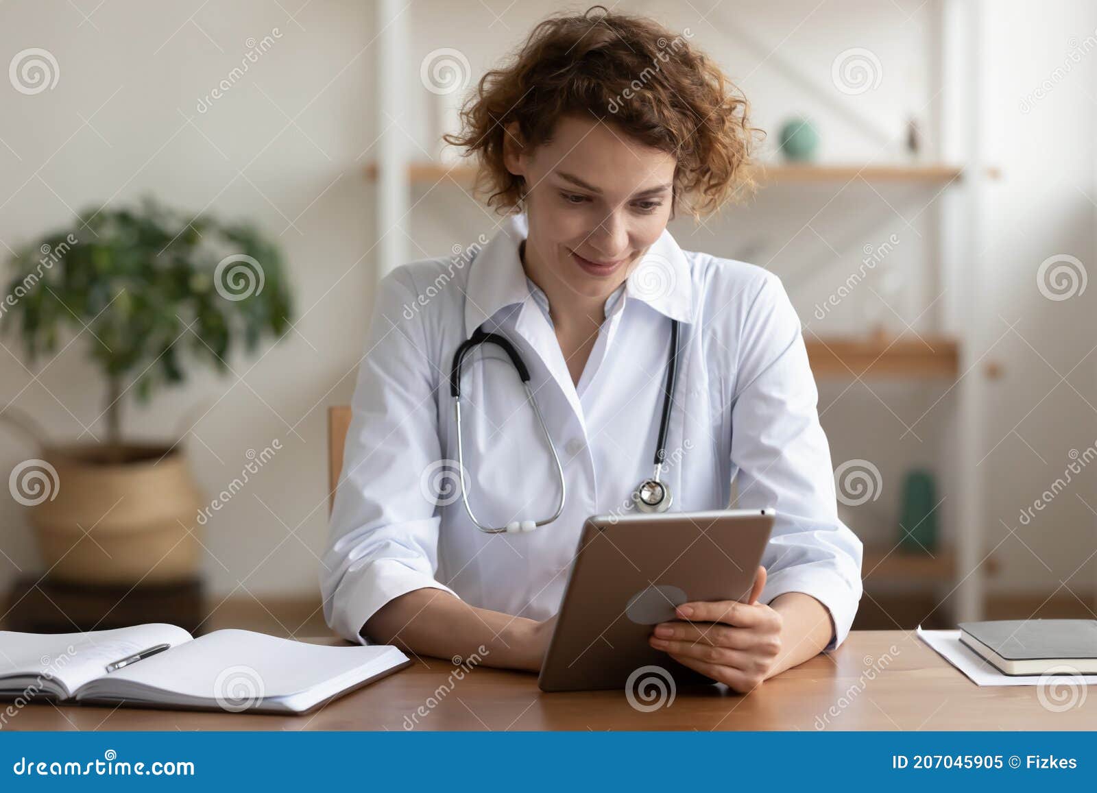 happy young female general practitioner using digital computer tablet.
