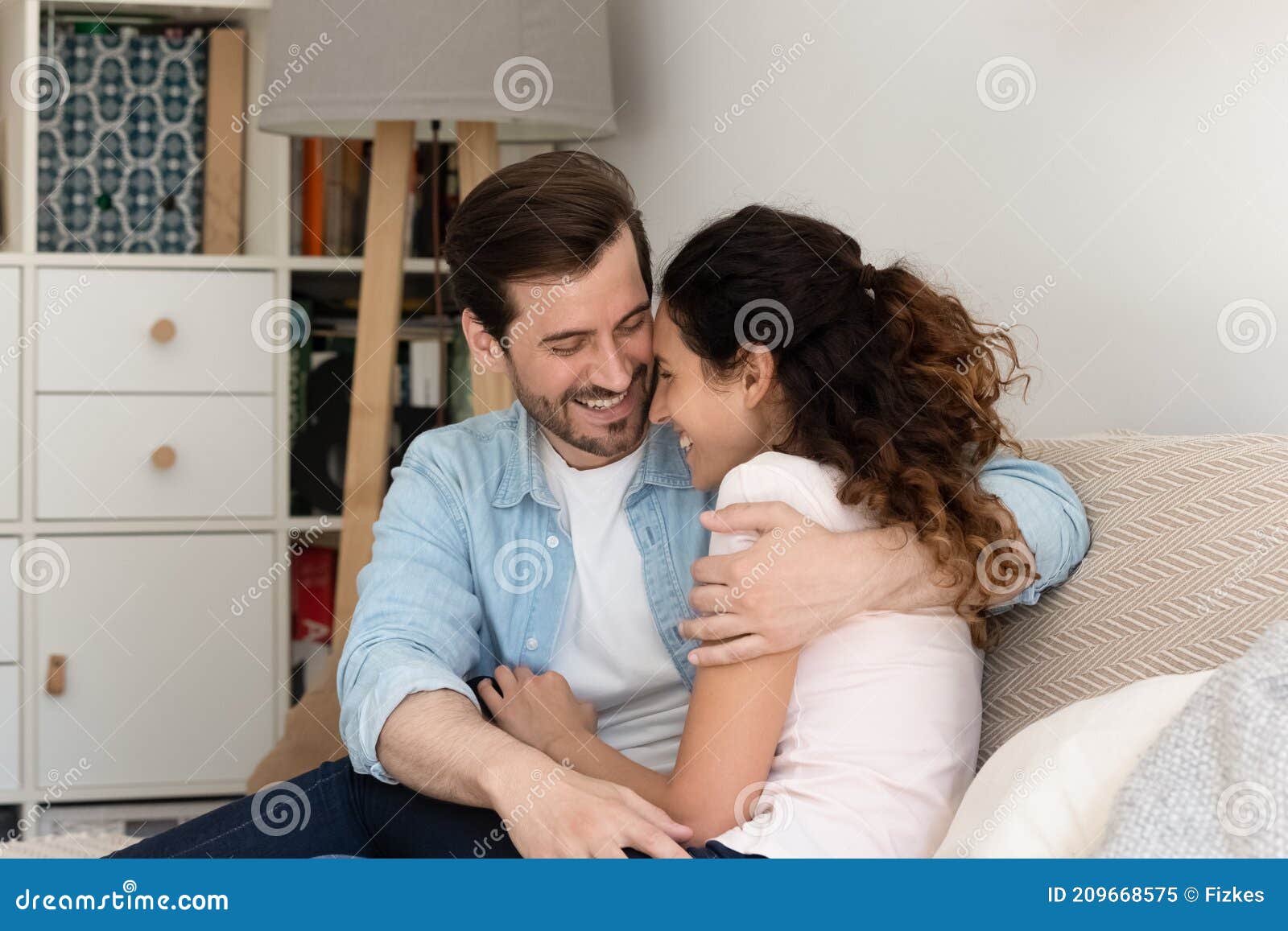 young couple house buyers cuddle on couch enjoy new home