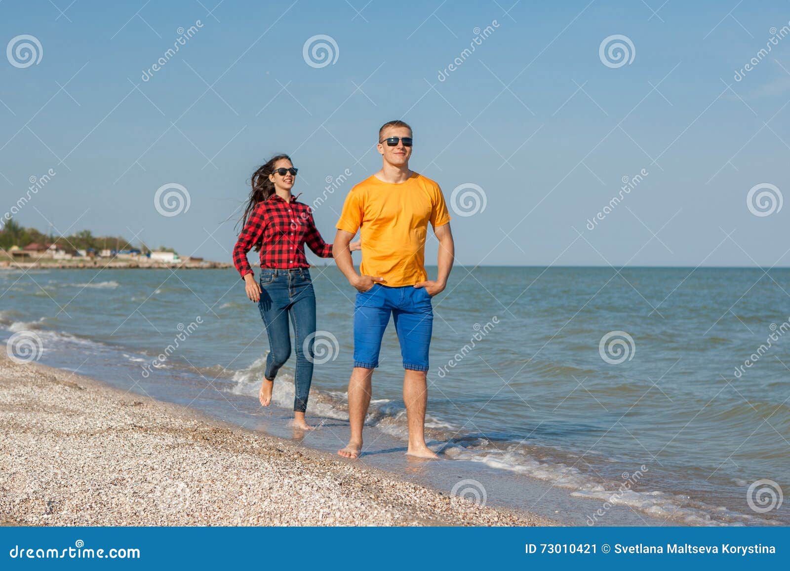 Happy young joyful guy and girl having fun on the beach, laughing together. During summer holidays vacation on sea. Beautiful energetic couple friends adolescents.