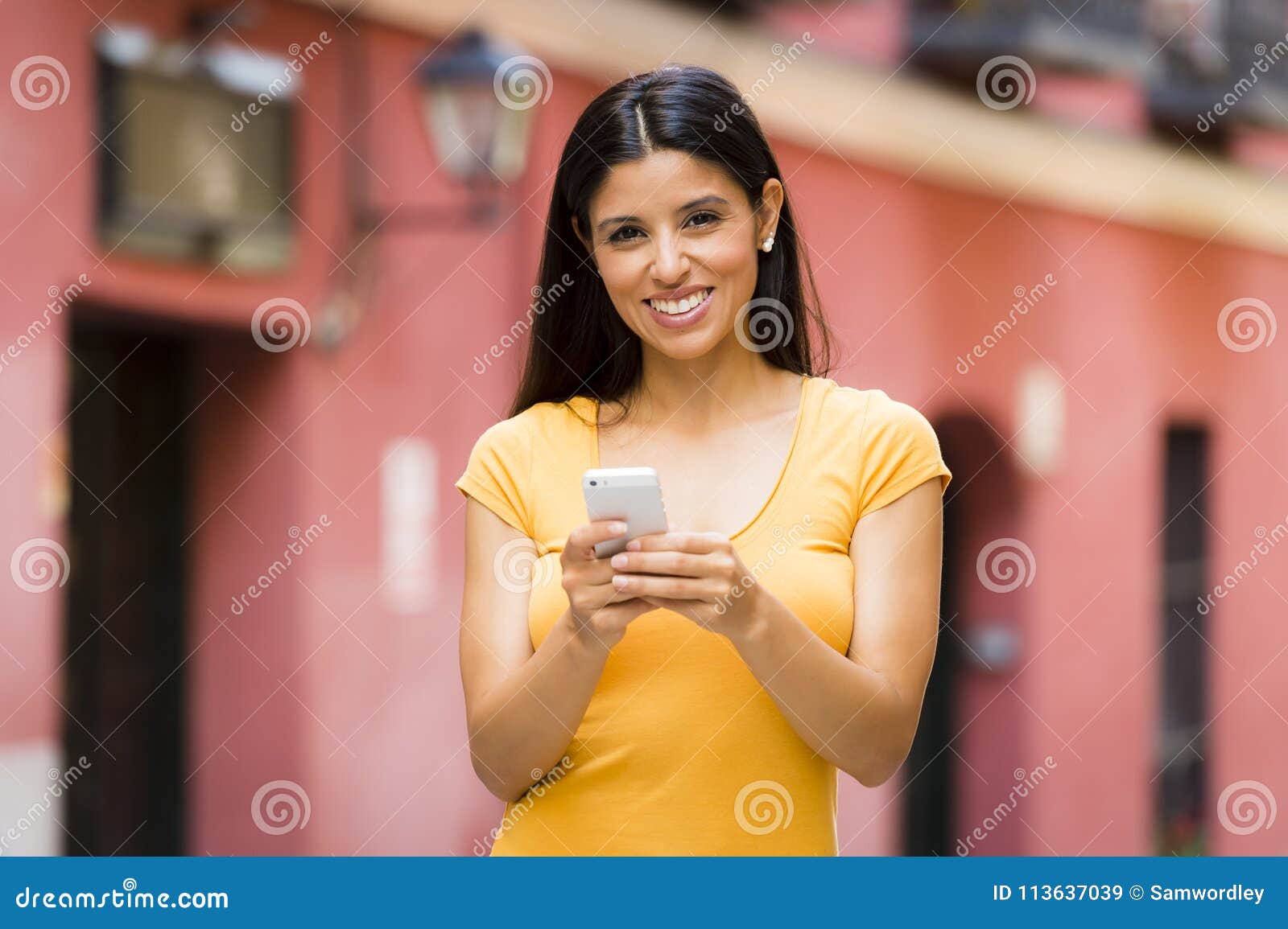 happy young latin woman talking and texting on smart phone