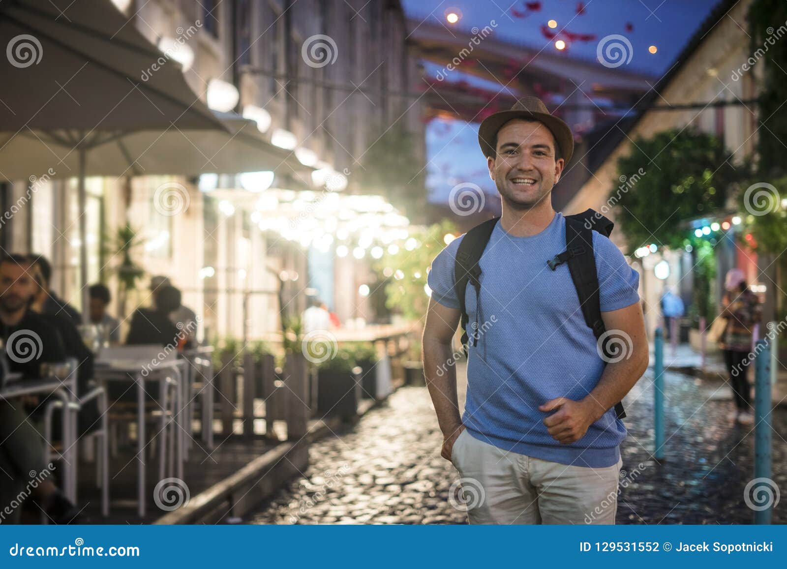 happy young man in blue shirt walking on in the city at the evevning