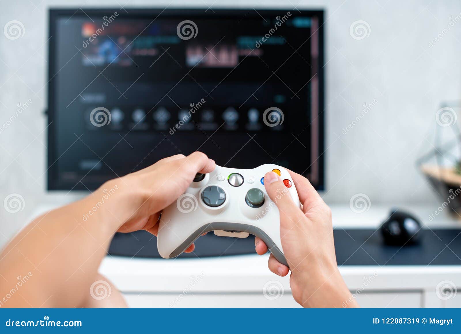 Happy young man playing and winning online game on computer. Back view of  gamer with video console gamepad controller. Competitive gaming, electronic  sports, technology, gaming, entertainment concept. Stock Photo