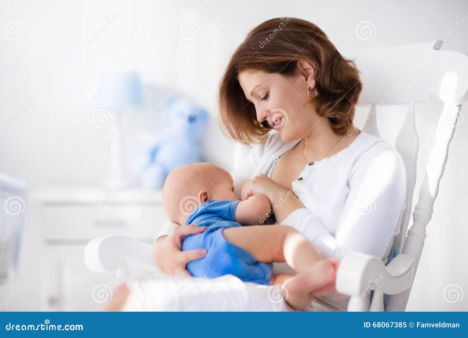 rocking chair and blue crib. Nursery interior. Mother playing with